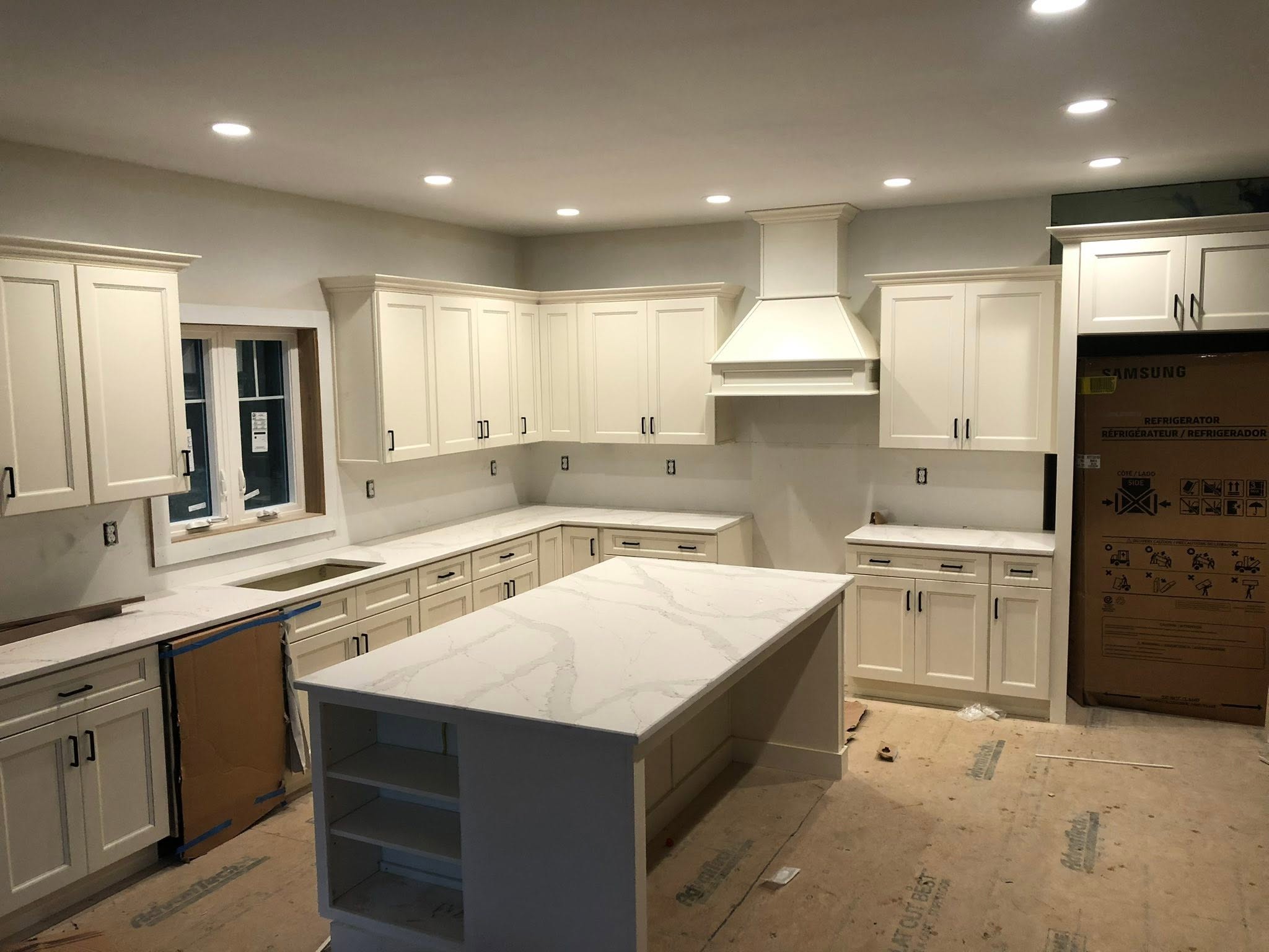 White custom kitchen cabinets with quartz counters and a center island